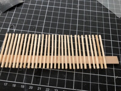Wood sticks are glued onto a popsicle stick to create a fence on the loft floor Wood sticks